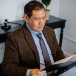 Advogado consulta um relatório em uma pasta sobre a mesa de um escritório.