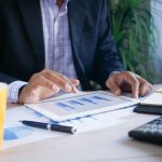 Homem analisa dados financeiros em um tablet no escritório.
