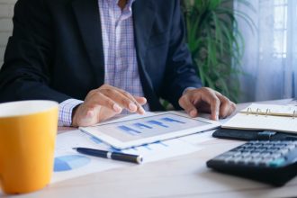 Homem analisa dados financeiros em um tablet no escritório.