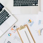 Laptops, gráficos e relatórios dispostos sobre uma mesa para análise de dados financeiros