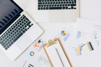 Laptops, gráficos e relatórios dispostos sobre uma mesa para análise de dados financeiros