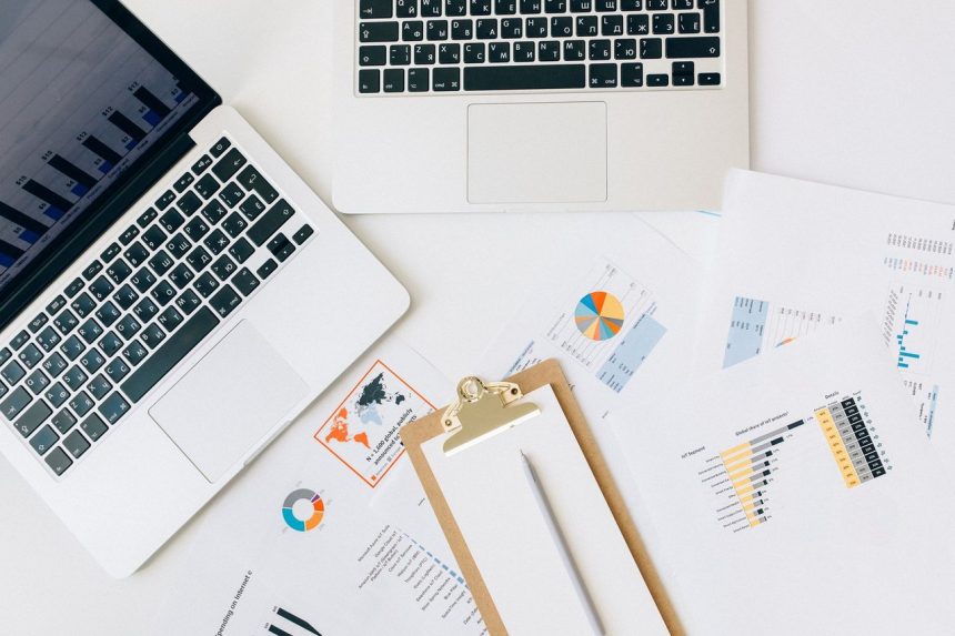 Laptops, gráficos e relatórios dispostos sobre uma mesa para análise de dados financeiros