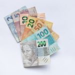 Cédulas brasileiras de diferentes valores dispostas em leque sobre fundo branco.