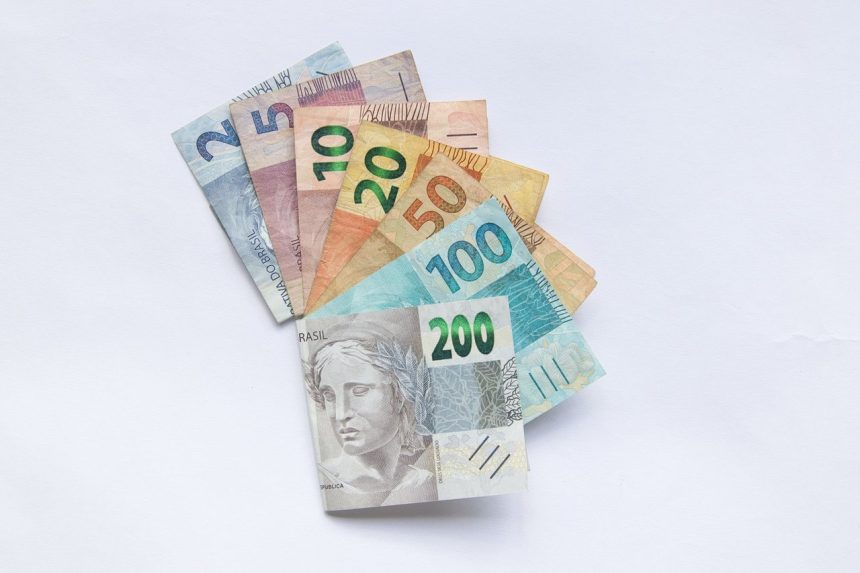 Cédulas brasileiras de diferentes valores dispostas em leque sobre fundo branco.