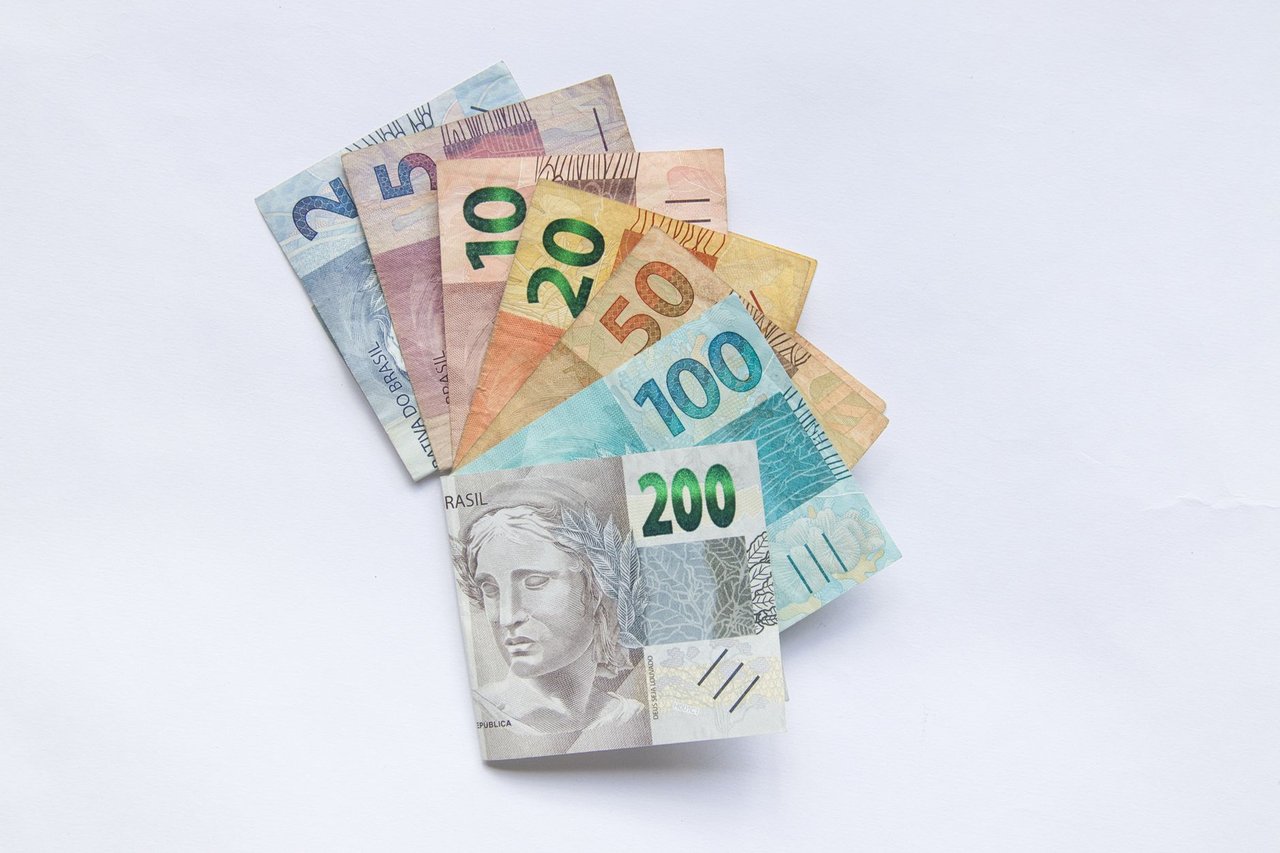 Cédulas brasileiras de diferentes valores dispostas em leque sobre fundo branco.