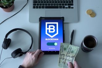 Tablet com representação de tecnologia blockchain, dinheiro em espécie e itens de escritório sobre uma mesa.