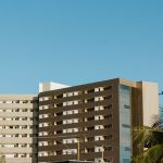 Edifício contemporâneo em Palmas, no Tocantins, cercado por palmeiras sob céu azul.