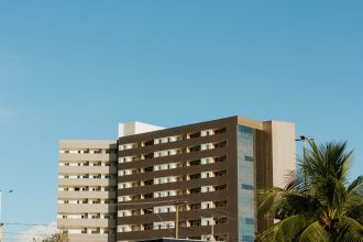 Edifício contemporâneo em Palmas, no Tocantins, cercado por palmeiras sob céu azul.
